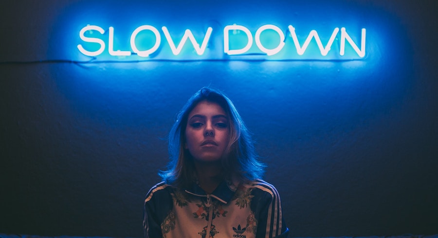 Young woman under neon sign "Slow Down"